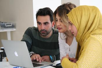 Three people looking at a laptop together