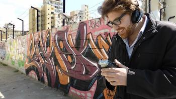 A man wearing headphones standing in front of a graffiti wall
