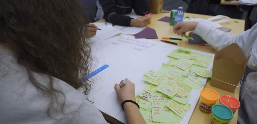 A teenager writing on sticky notes during a discussion